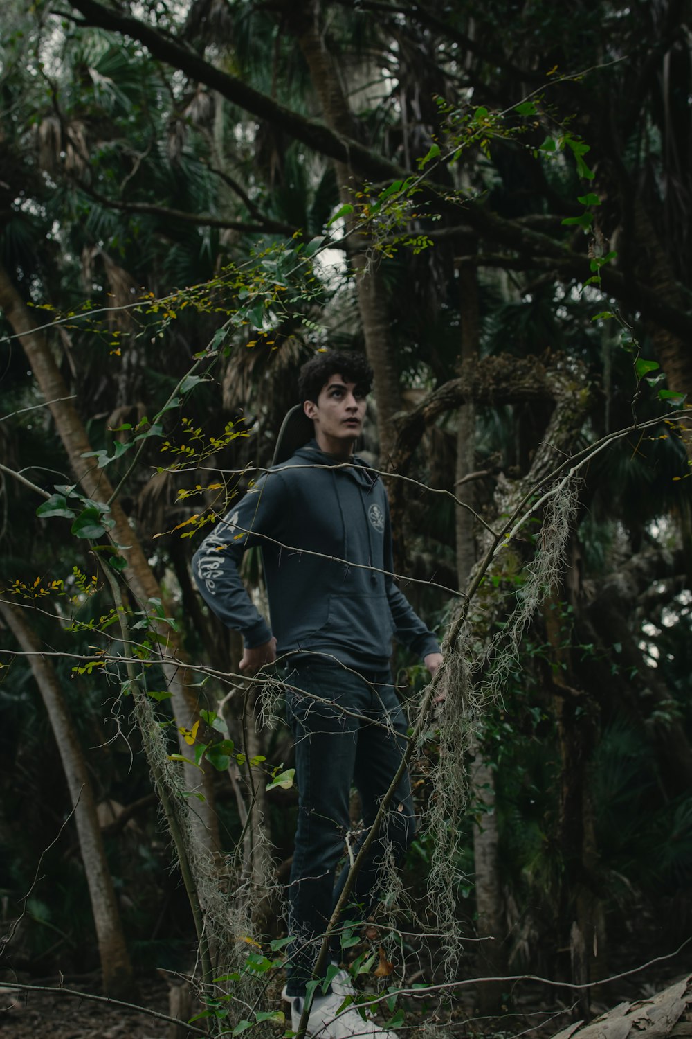 man in black leather jacket standing near green trees during daytime