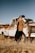 man in brown jacket standing beside white crew cab truck during daytime