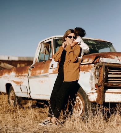 man in brown jacket standing beside white crew cab truck during daytime