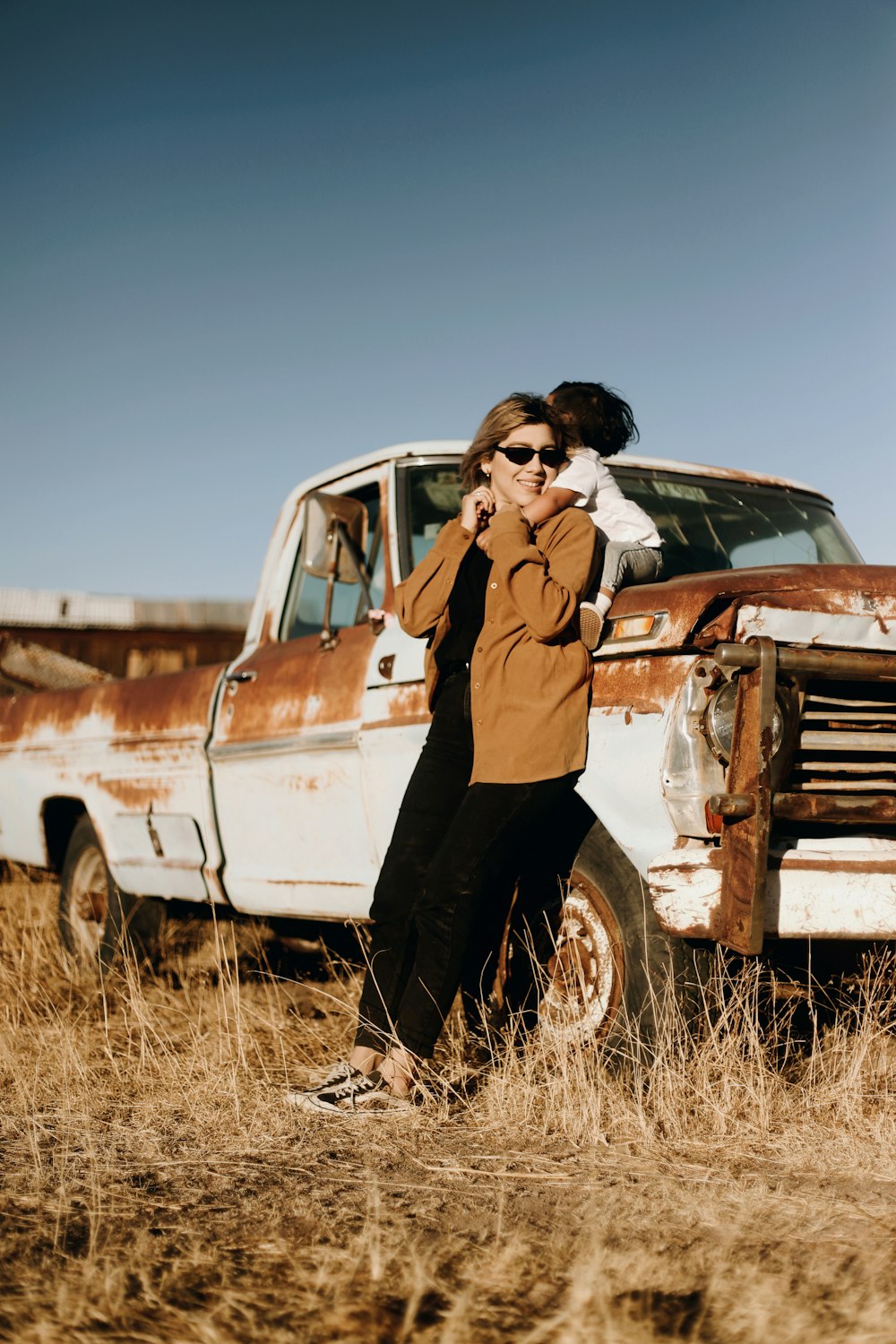 man in brown jacket standing beside white crew cab truck during daytime