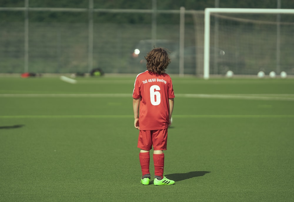 man in red soccer jersey standing on green field