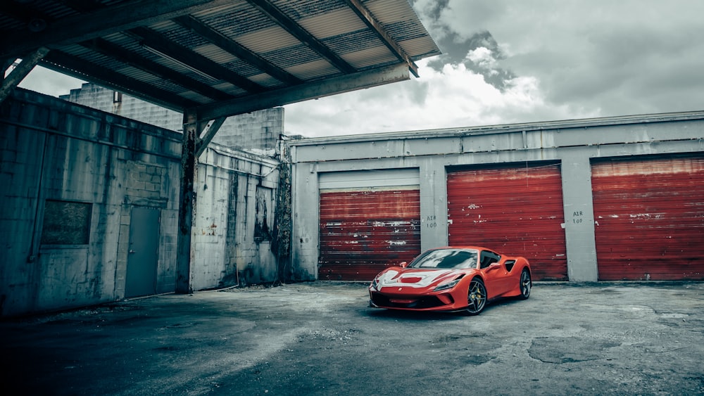 Porsche 911 rojo y blanco aparcado junto a un edificio de hormigón gris durante el día