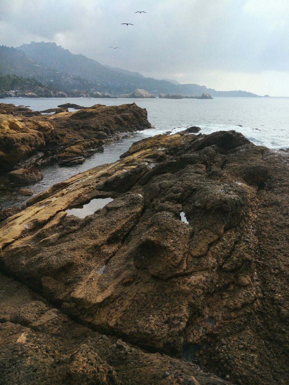 brown rock formation near body of water during daytime