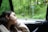 A happy customer using a travel pillow in a car.