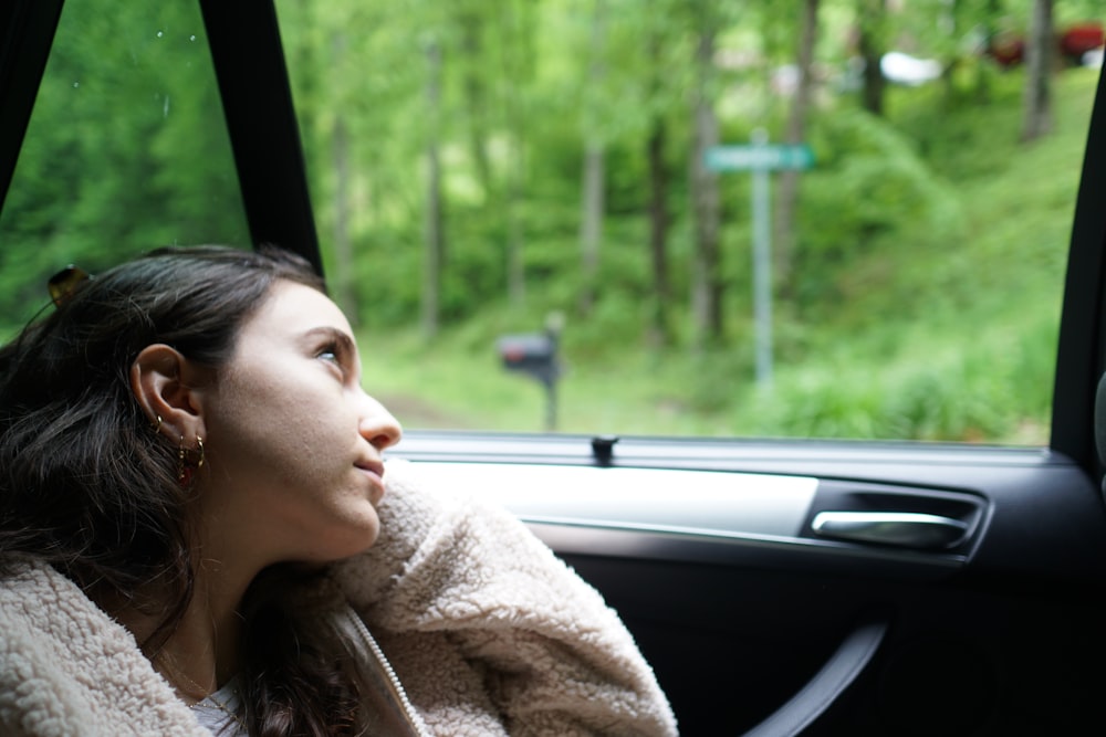 woman in beige coat sitting inside car during daytime