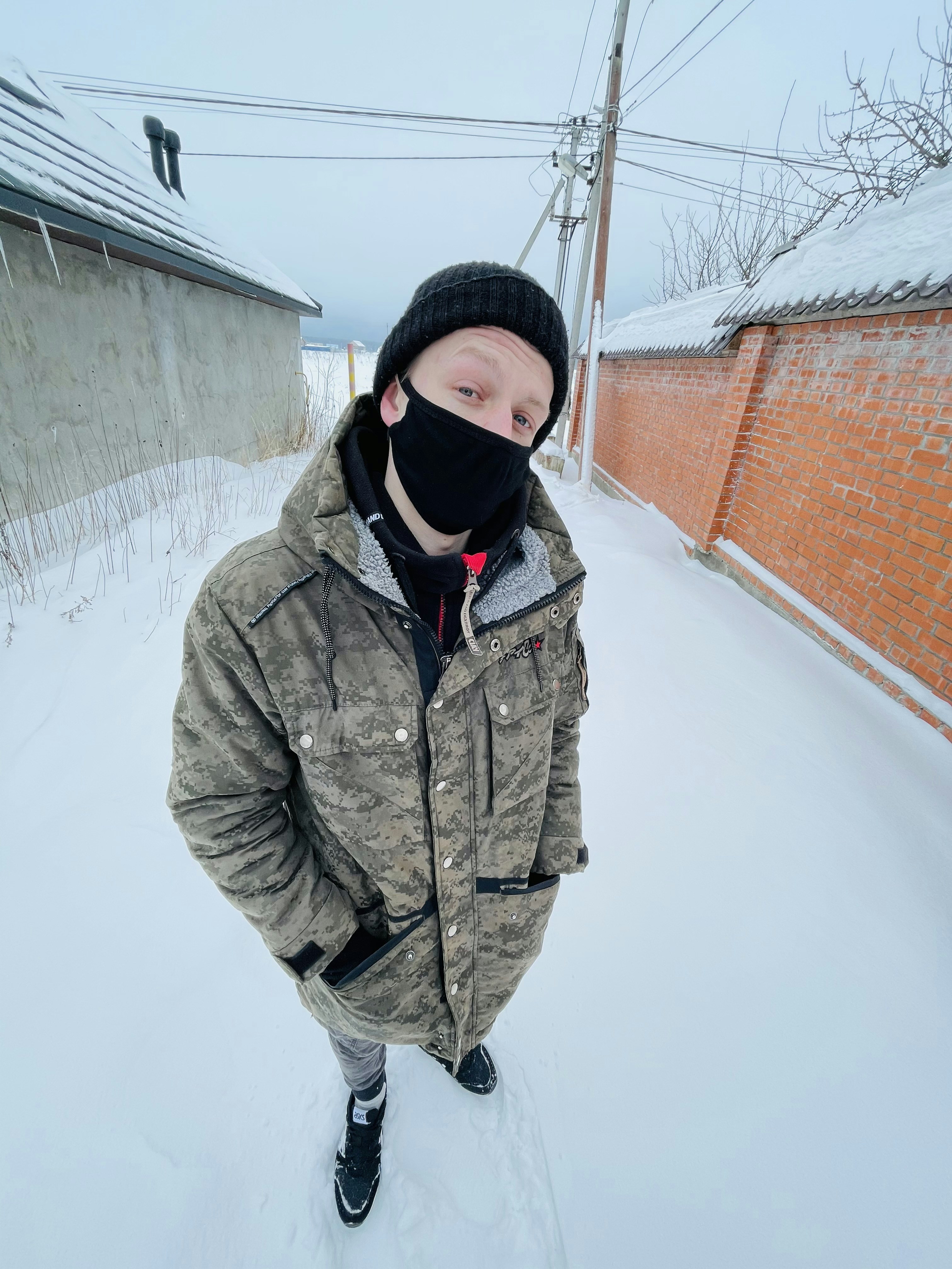 woman in gray coat and black knit cap standing on snow covered ground during daytime