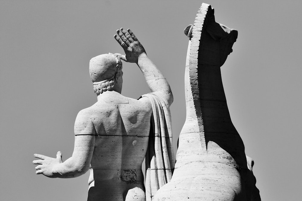 grayscale photo of man holding glass bottle statue