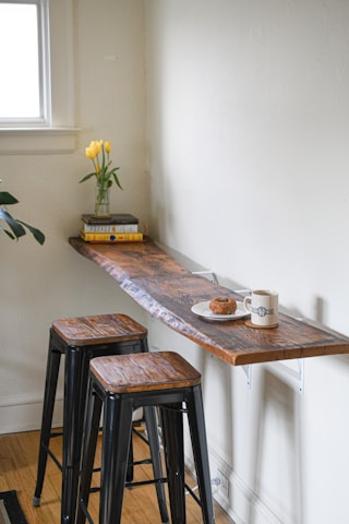 Two elegant bar stools paired with a minimalist wall-mounted glass rack.