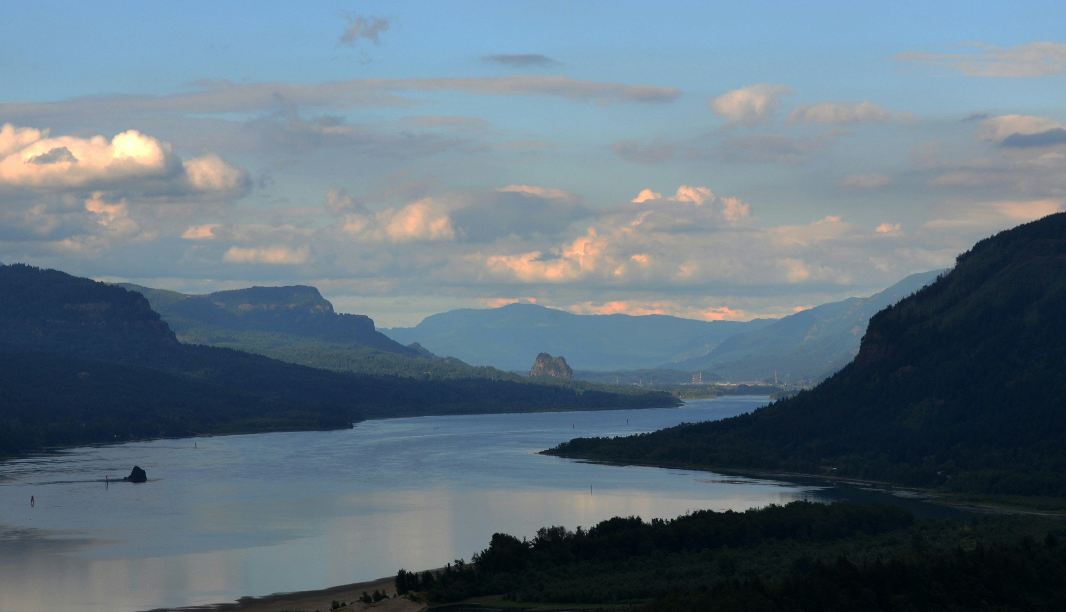 body of water near mountain under cloudy sky during daytime