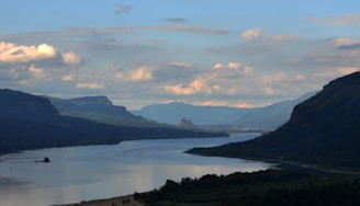 A gentle sky blue river winding through misty gray mountains under a bright yellow sun rising.