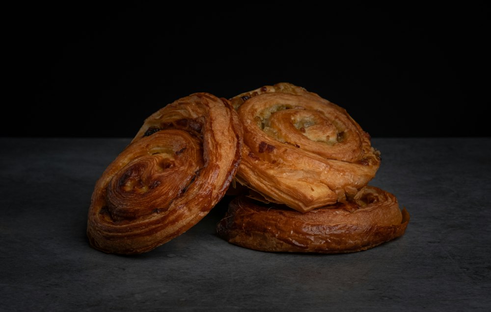 Two cinnamon swirl pastries on a dark surface