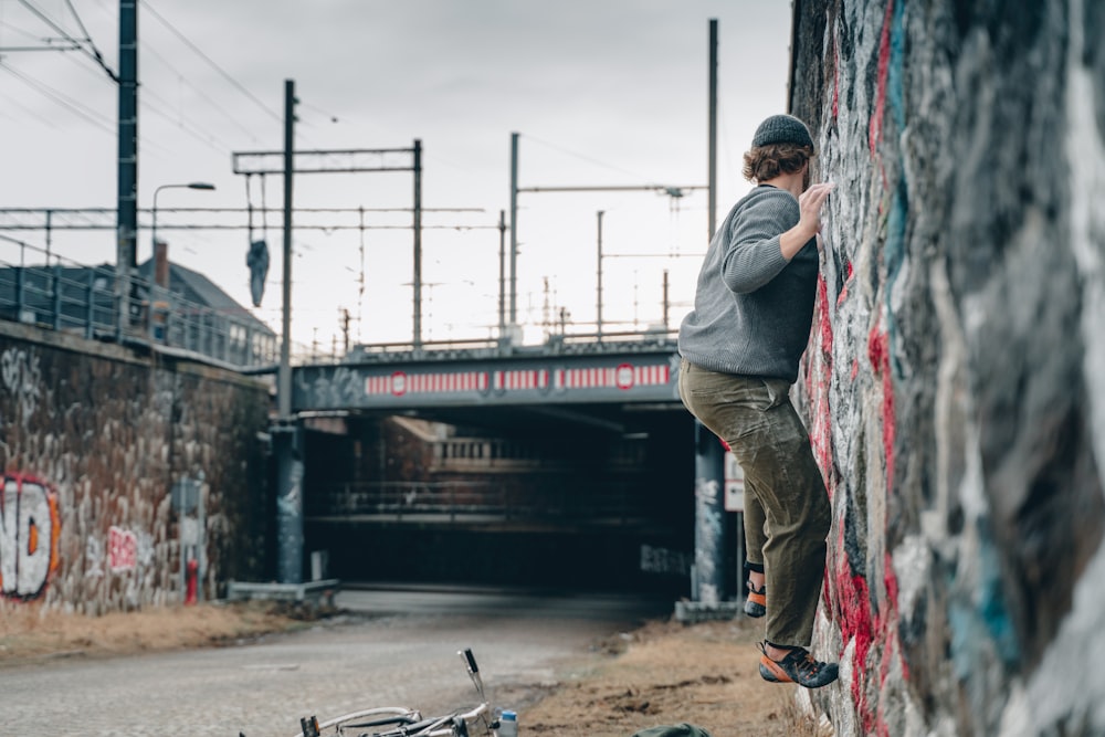 man in grey jacket and grey pants holding black skateboard