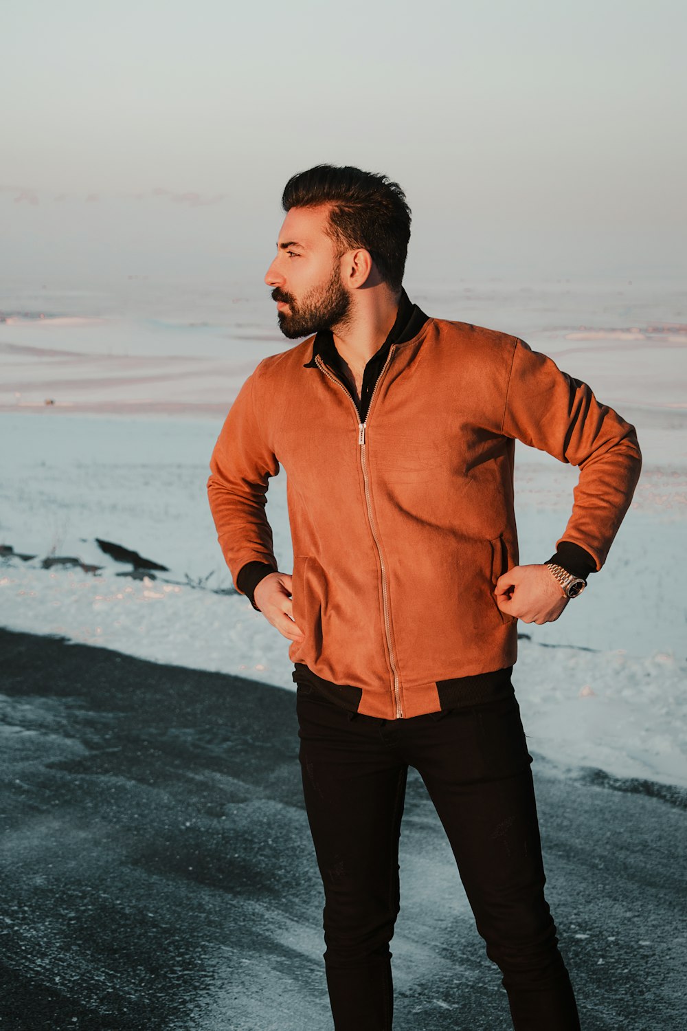 man in brown zip up jacket standing on beach during daytime