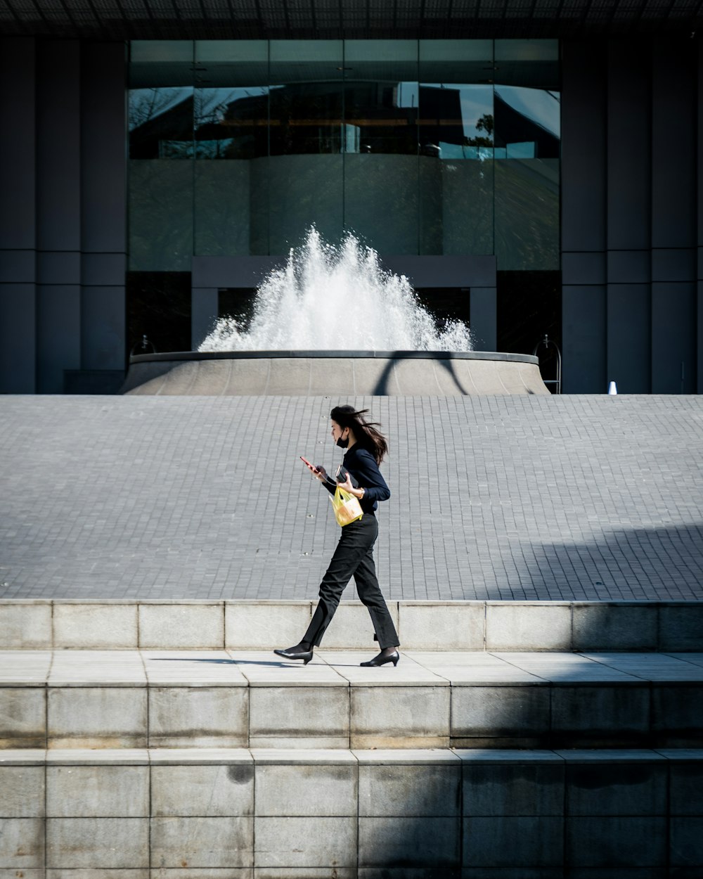 woman in black pants and black boots walking on gray concrete stairs during daytime