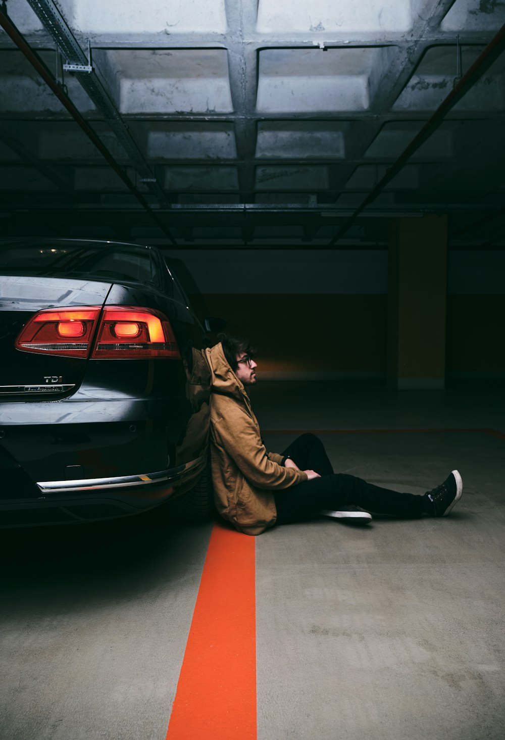 woman in black pants and black leather boots standing beside black car