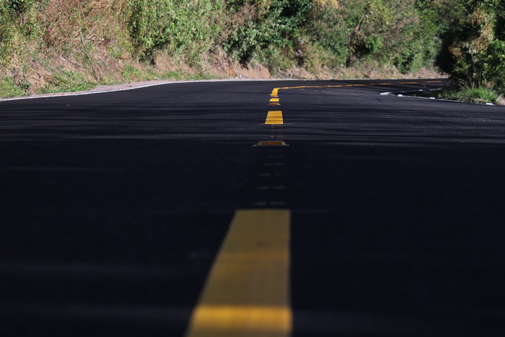 black asphalt road between green grass field during daytime