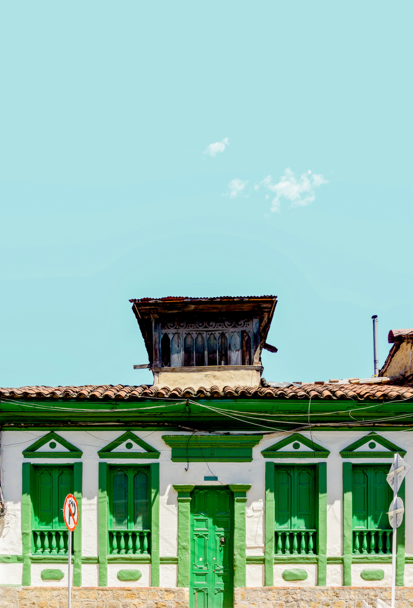 Green painted colonial building facade in the La Candelaria neighbourhood of Bogota Colombia with blue sky above
