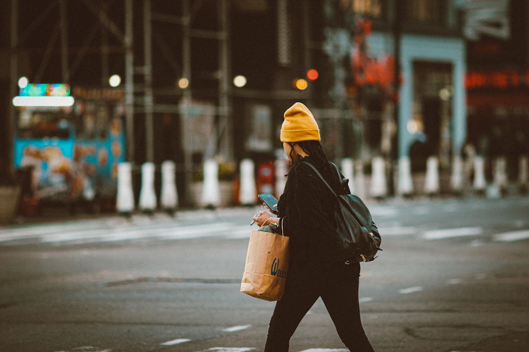 person in black jacket and yellow knit cap carrying brown plastic bucket