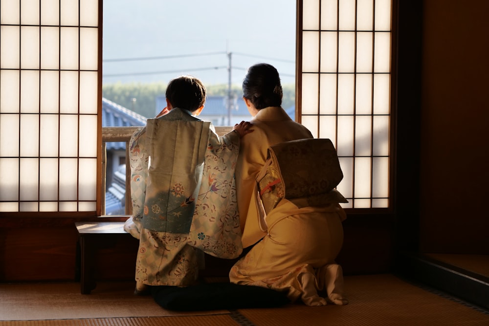 2 person sitting on chair near window during daytime