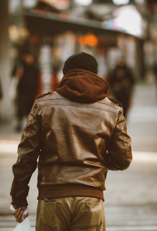 Person carrying a sleek leather tote bag while walking in an urban setting.