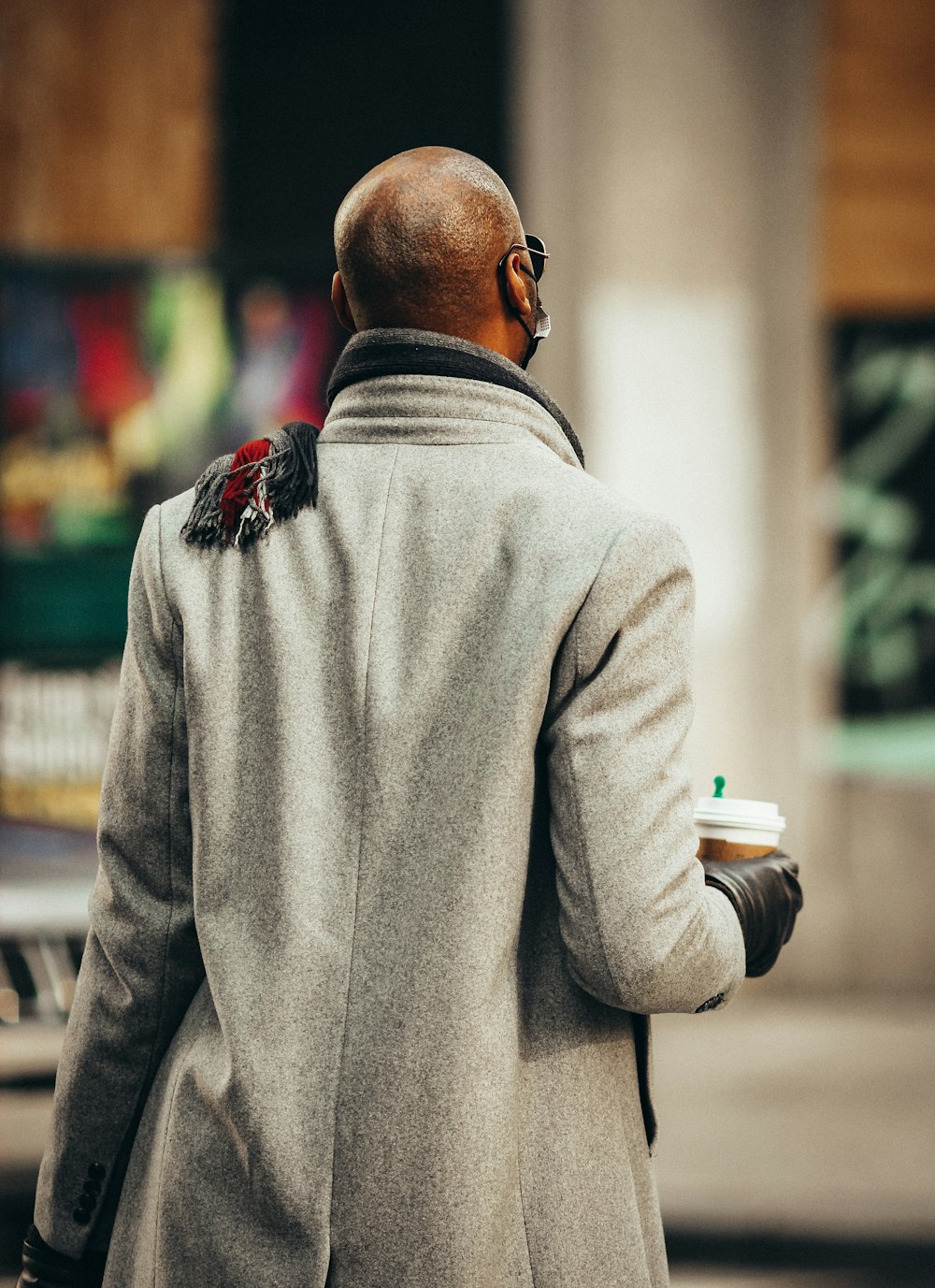 man in gray sweater holding white cup