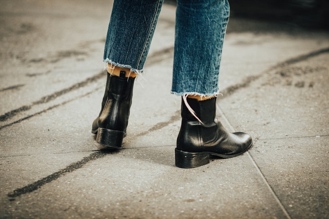 person in blue denim jeans and black leather boots