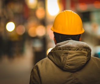 person in yellow hard hat and brown jacket