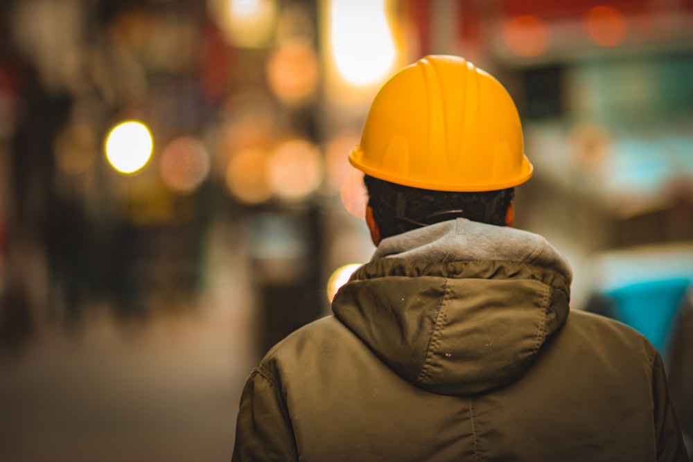 person in yellow hard hat and brown jacket