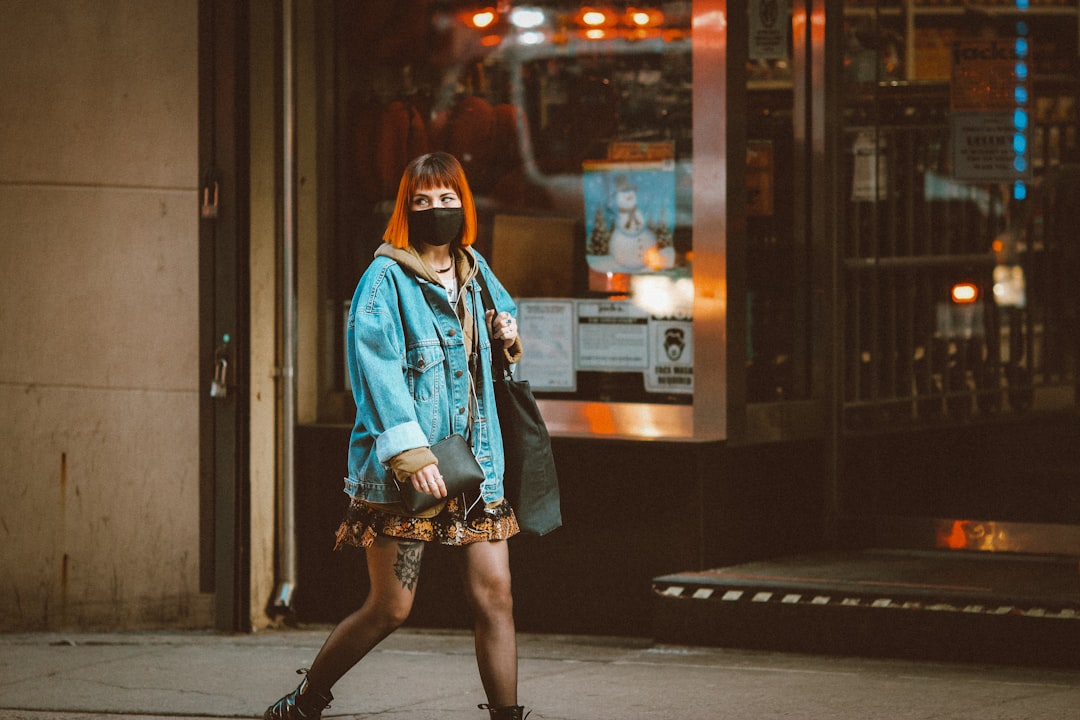 woman in blue denim jacket standing on sidewalk during nighttime