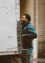 A friendly contractor wearing a work jacket stands beside a rugged pickup truck with a backdrop of a Canadian home exterior.