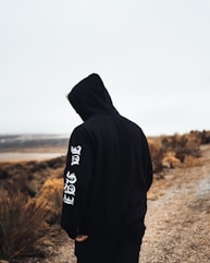 person in black and white hoodie standing on brown field during daytime