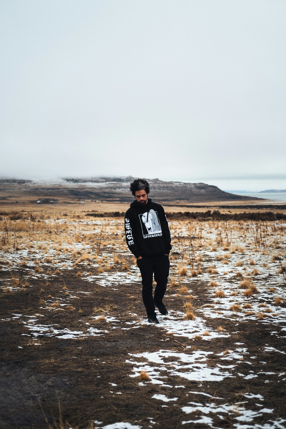 man in black jacket standing on brown field during daytime