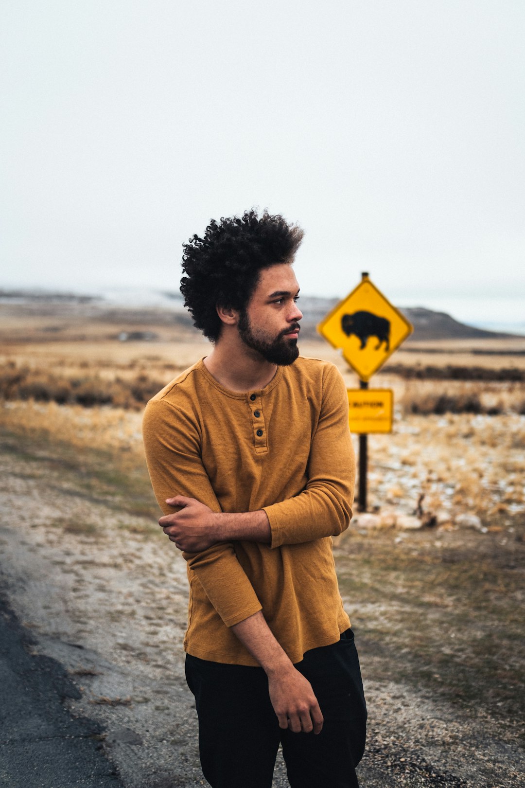 man in brown sweater standing on gray sand during daytime