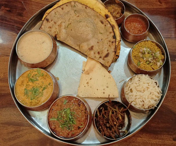 A colorful thali featuring an array of South Indian vegetarian dishes, each served in traditional stainless steel bowls.