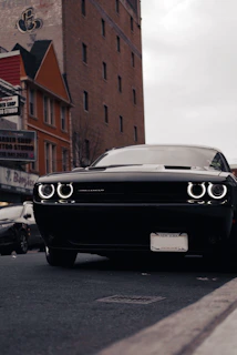 black bmw car parked beside brown building during daytime