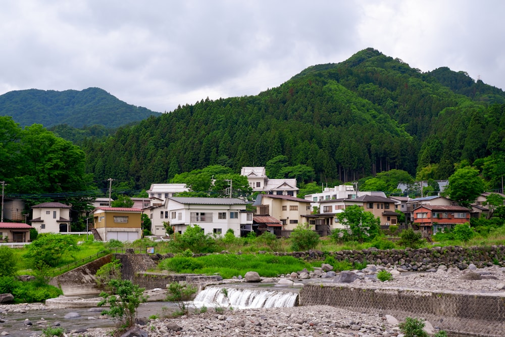 white and brown houses near green mountain under white cloudy sky during daytime