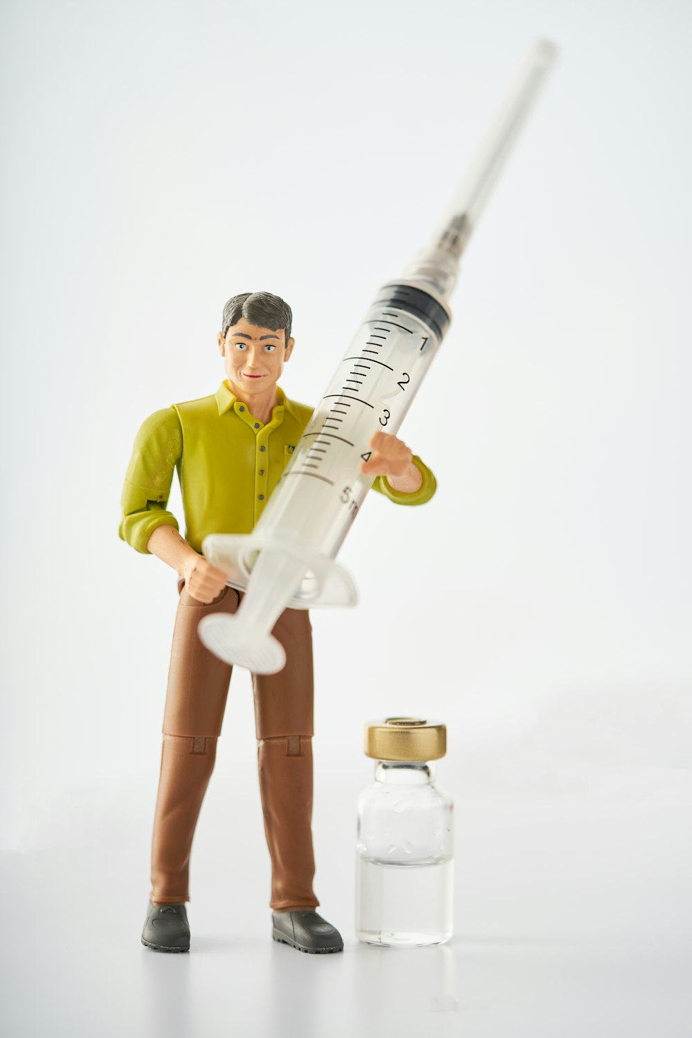 Un uomo giocattolo che tiene un syquet accanto a una bottiglia di medicina