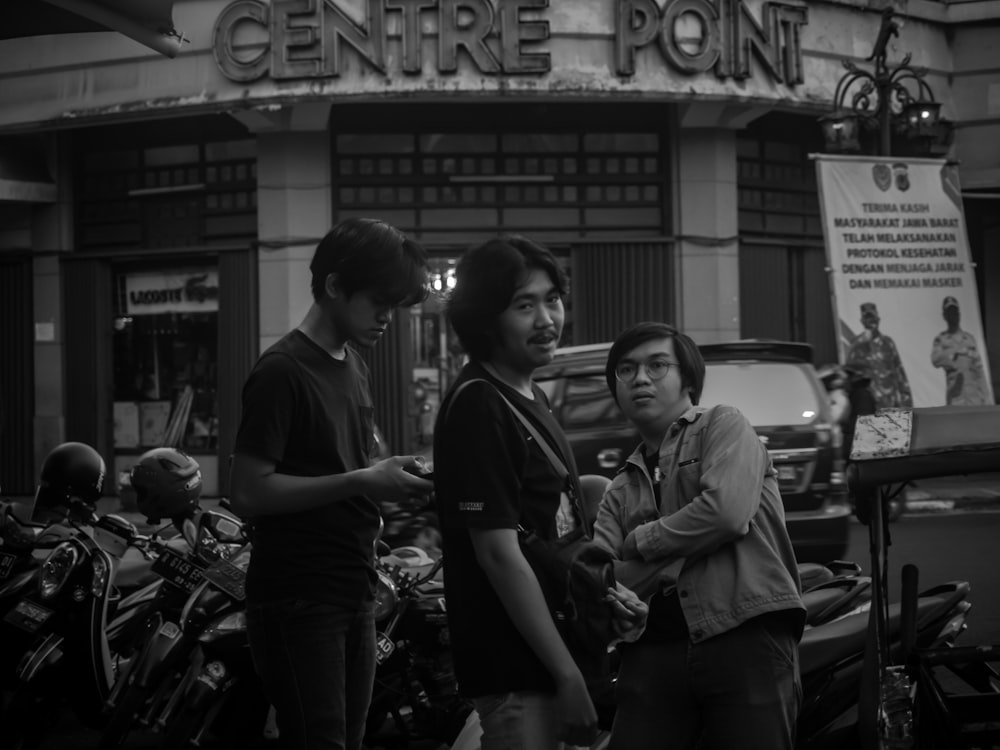 grayscale photo of man and woman standing beside motorcycle