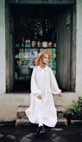 woman in white long sleeve dress standing near green plant