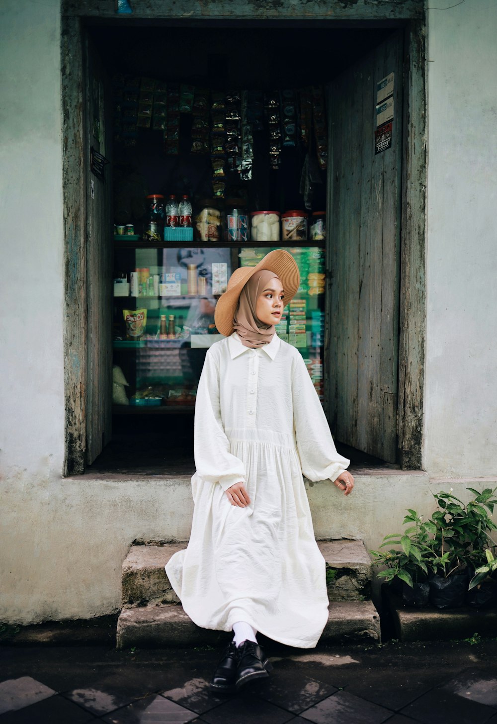 woman in white long sleeve dress standing near green plant