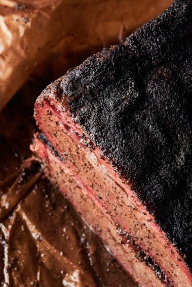 Close-up of a juicy, perfectly smoked brisket slice with a dark, flavorful bark and tender pink smoke ring.