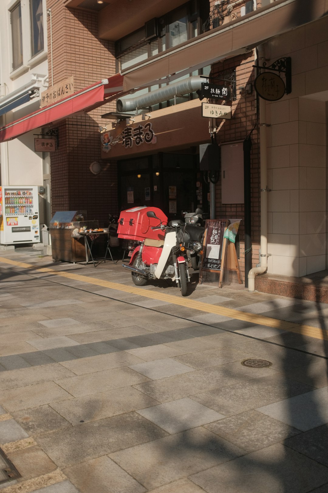 red and white bicycle parked beside brown building during daytime