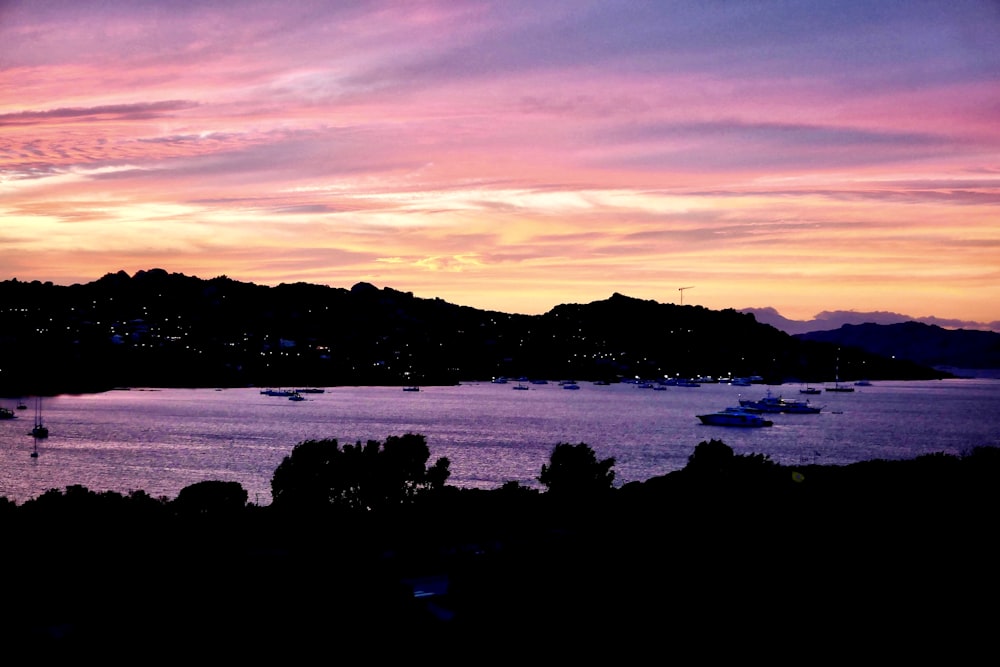 silhouette of mountain near body of water during sunset