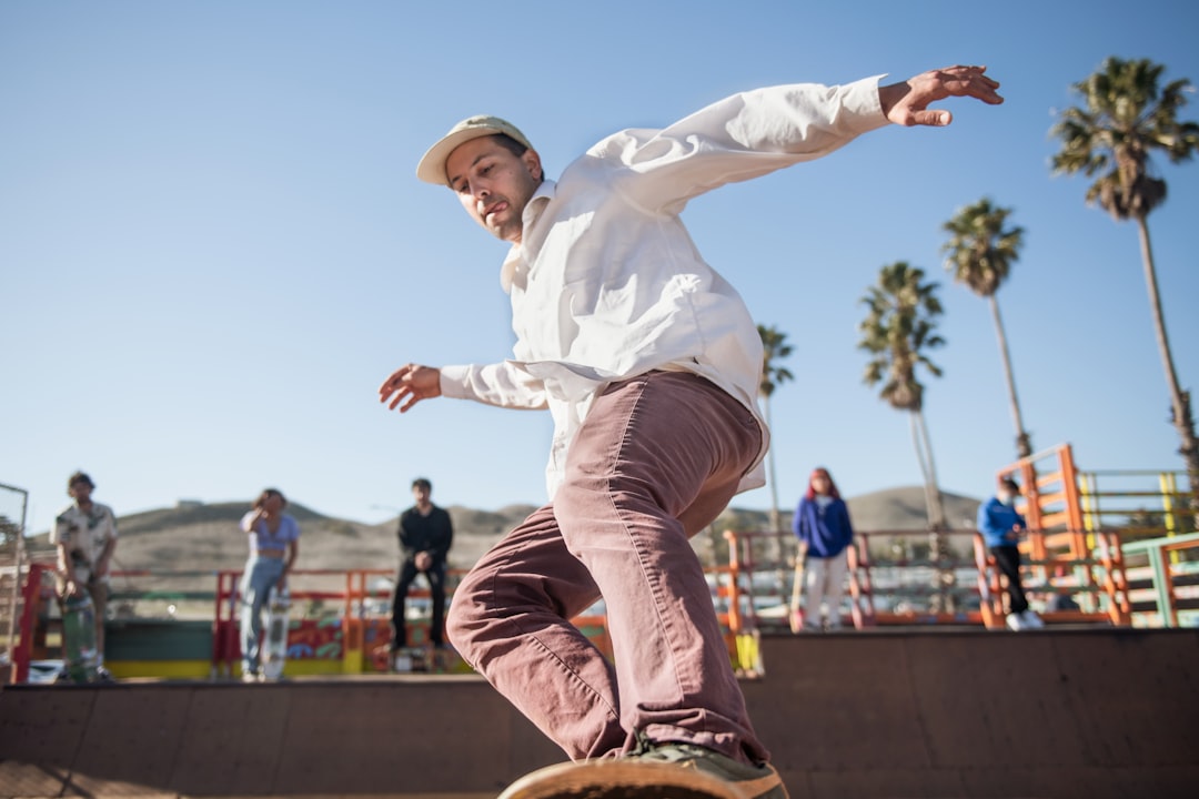 man in white long sleeve shirt and brown pants jumping on air during daytime