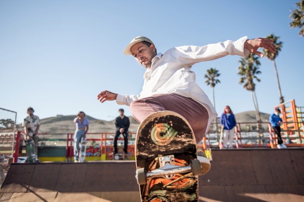 man in white dress shirt and brown pants wearing brown hat jumping during daytime