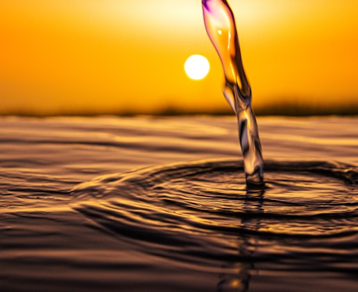 water drop on brown sand during sunset