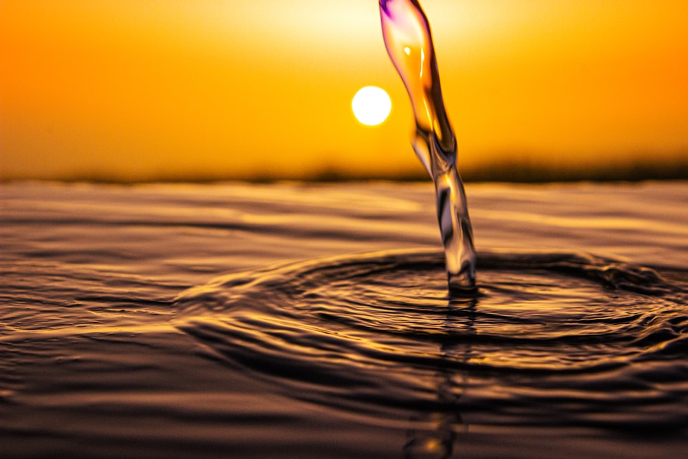 Wassertropfen auf braunem Sand bei Sonnenuntergang