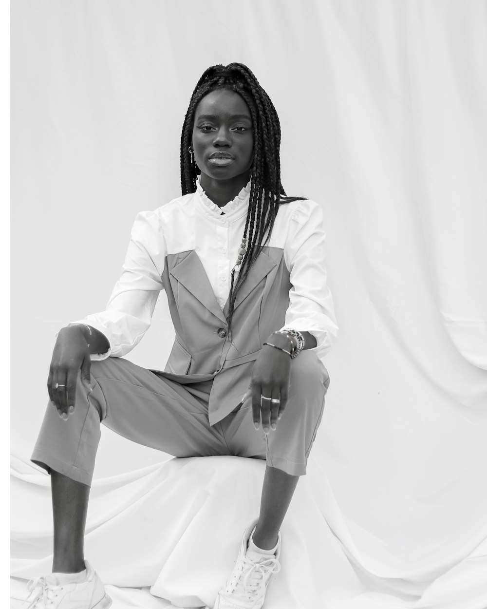 woman in white blazer and brown pants sitting on white textile