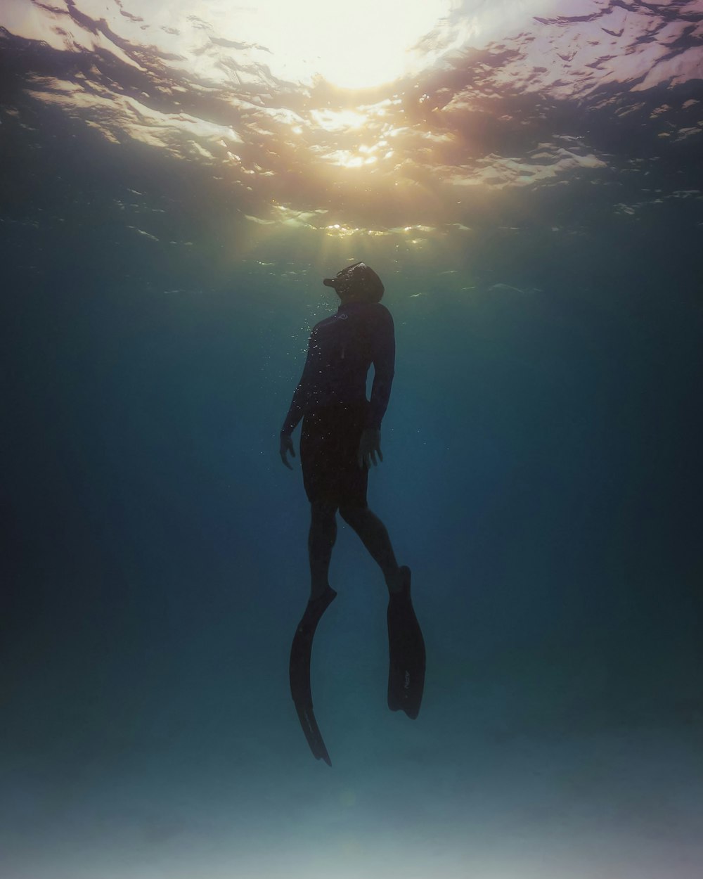 man in black wet suit under blue sky