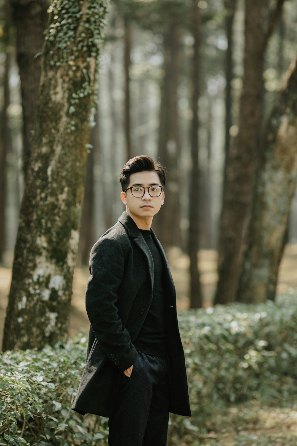 man in black jacket wearing black sunglasses standing near tree during daytime